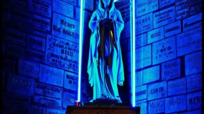 A traditional stone statue of the Virgin Mary, except her halo and the surround is blue neon tubes giving the whole thing a cyberpunk aura.